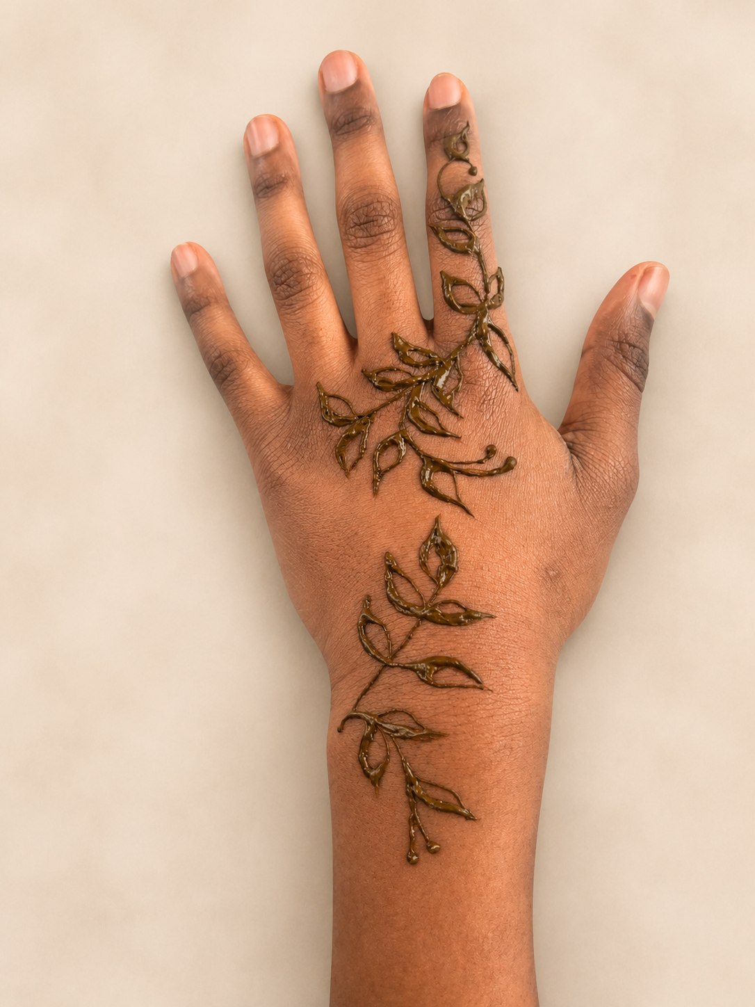Delicate leaf vine henna in warm golden tone trailing down the hand