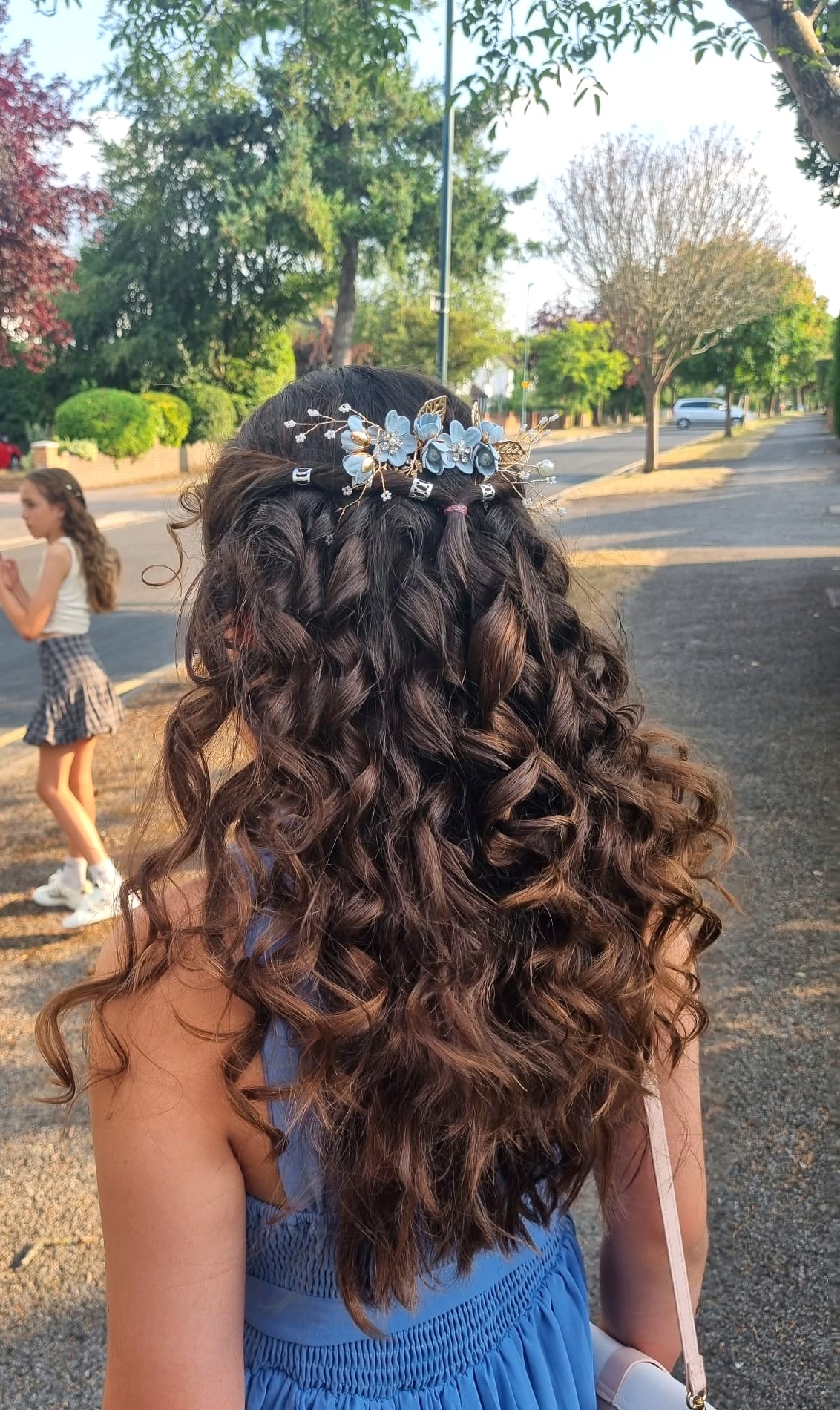 Waterfall braid with flowing curls and a blue floral hair piece